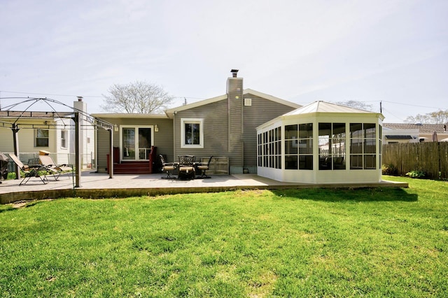 back of property with a lawn, fence, a patio, a sunroom, and a gazebo