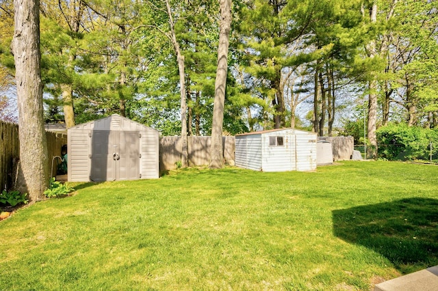 view of yard with a fenced backyard, a shed, and an outbuilding