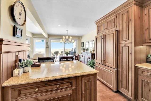 279 Dune Rd Unit 2, Westhampton Beach, NY 11978 - kitchen featuring a chandelier, brown cabinetry, light wood-style floors, light stone countertops, and recessed lighting