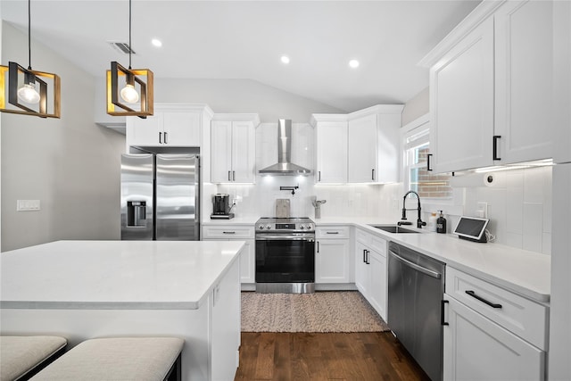 kitchen featuring a sink, lofted ceiling, wall chimney range hood, dark wood-style floors, and appliances with stainless steel finishes