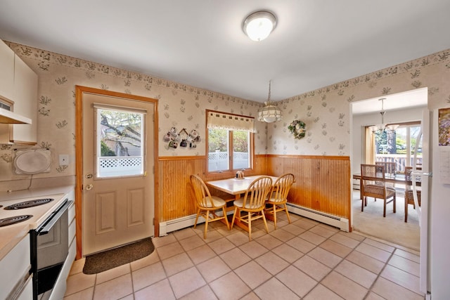 dining area featuring a baseboard radiator, a healthy amount of sunlight, wood walls, and a wainscoted wall