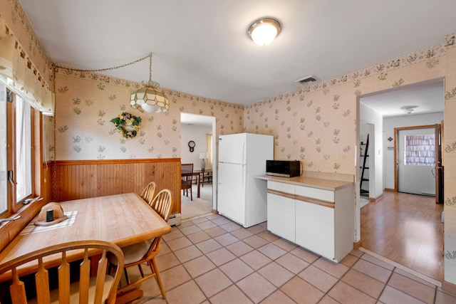 kitchen featuring freestanding refrigerator, wallpapered walls, wainscoting, and black microwave