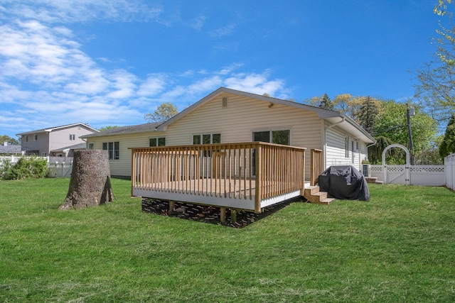 back of property featuring a fenced backyard, a wooden deck, and a lawn
