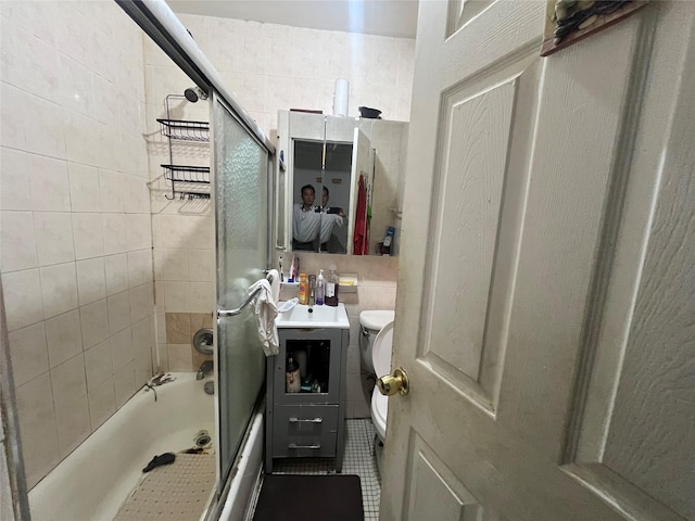 bathroom with toilet, tile patterned flooring, and bath / shower combo with glass door