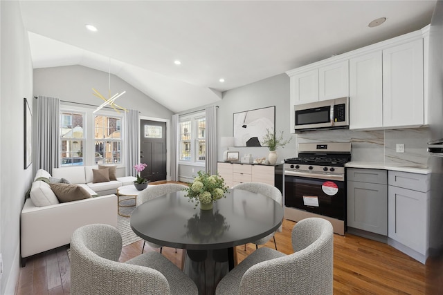 kitchen featuring light wood finished floors, stainless steel appliances, gray cabinets, vaulted ceiling, and recessed lighting