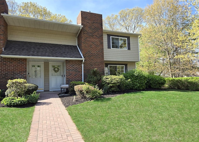 view of front of home featuring a shingled roof, a front lawn, and a chimney