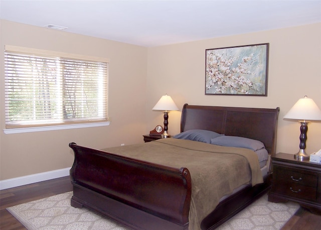 bedroom featuring baseboards, visible vents, and wood finished floors