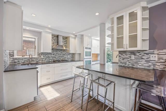 8702 Chevy Chase St, Jamaica Estates, NY 11432 - kitchen featuring a sink, wall chimney exhaust hood, dark countertops, a peninsula, and backsplash