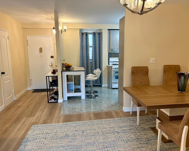 dining room featuring a chandelier, baseboards, and wood finished floors