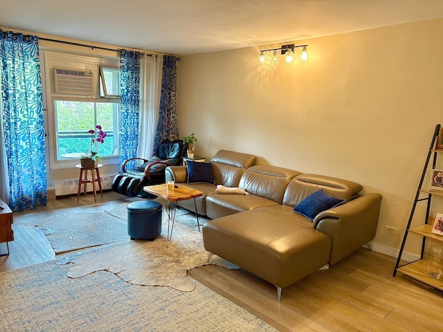 living area featuring a baseboard radiator, baseboards, a wall unit AC, and wood finished floors