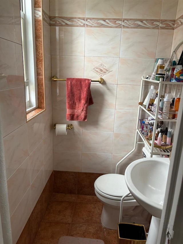 half bath with tile walls, toilet, and a sink