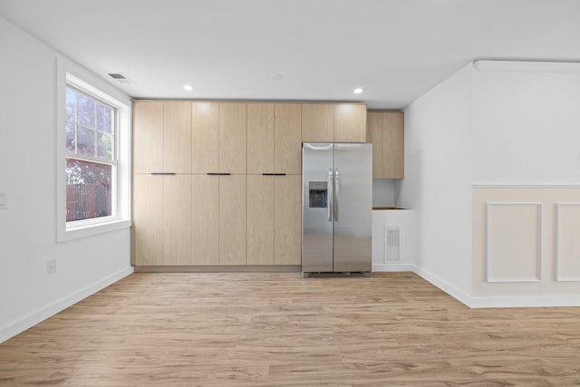 kitchen with light wood-style flooring, stainless steel refrigerator with ice dispenser, and light brown cabinetry