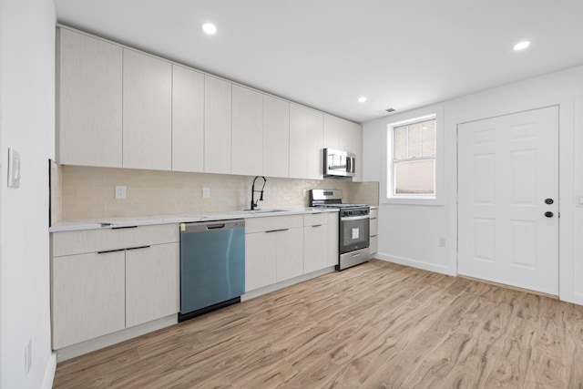 kitchen with light wood finished floors, light countertops, stainless steel appliances, and a sink