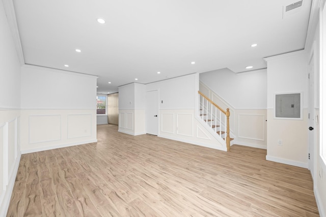 unfurnished living room with electric panel, stairs, a decorative wall, recessed lighting, and light wood-style floors