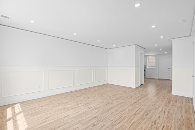 empty room with recessed lighting, a decorative wall, a wainscoted wall, and light wood-style floors