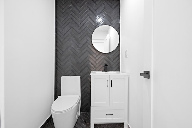 half bathroom with toilet, baseboards, and vanity