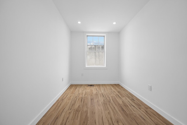 empty room featuring light wood-style flooring, baseboards, visible vents, and recessed lighting