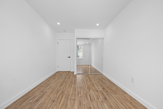 unfurnished bedroom with a closet, light wood-style flooring, baseboards, and recessed lighting