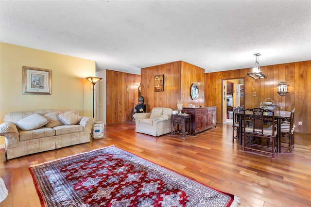 living area with wood walls, wood-type flooring, and a textured ceiling