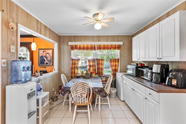 dining room featuring a ceiling fan, light tile patterned flooring, crown molding, and wood walls