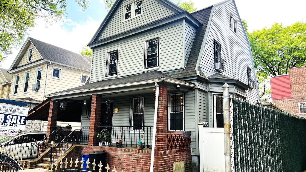 4308 68th St Unit 2Family, Woodside, NY 11377 - view of front of house featuring covered porch, roof with shingles, a gambrel roof, and fence