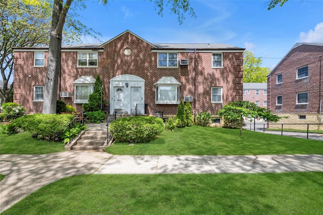 view of front facade featuring fence, a front lawn, and brick siding