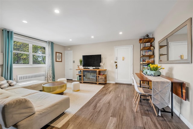 living room featuring baseboards, radiator, recessed lighting, and wood finished floors