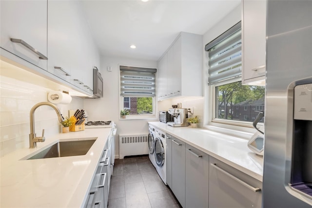 kitchen featuring radiator, stainless steel fridge, a sink, and a wealth of natural light