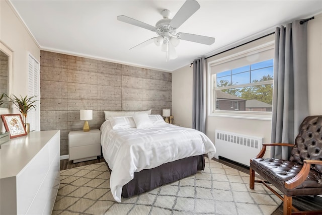 bedroom featuring crown molding, light wood-type flooring, ceiling fan, and radiator heating unit
