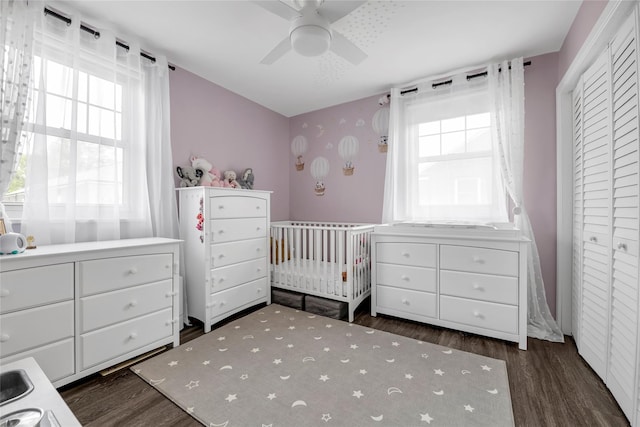 bedroom with a ceiling fan, a nursery area, and wood finished floors