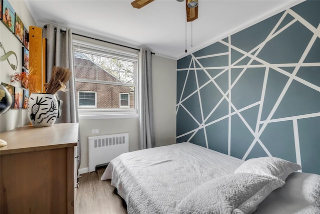 bedroom with baseboards, radiator heating unit, and wood finished floors