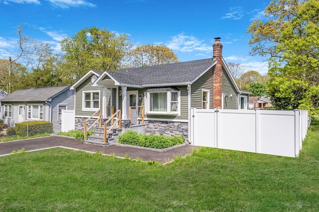 73 S Evergreen Dr, Selden, NY 11784 - view of front of house with stone siding, fence, a chimney, a front lawn, and roof with shingles