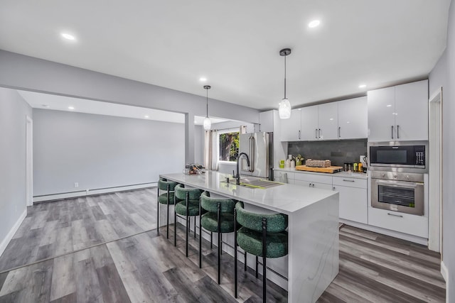 73 S Evergreen Dr, Selden, NY 11784 - kitchen with a sink, a breakfast bar, white cabinetry, decorative backsplash, and appliances with stainless steel finishes