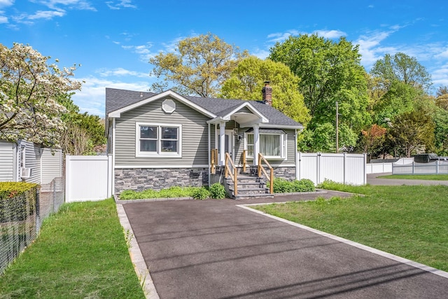 73 S Evergreen Dr, Selden, NY 11784 - bungalow-style home with stone siding, fence, a chimney, a shingled roof, and a front yard