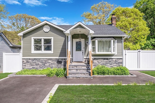 73 S Evergreen Dr, Selden, NY 11784 - view of front of property featuring a gate, roof with shingles, fence, stone siding, and a chimney