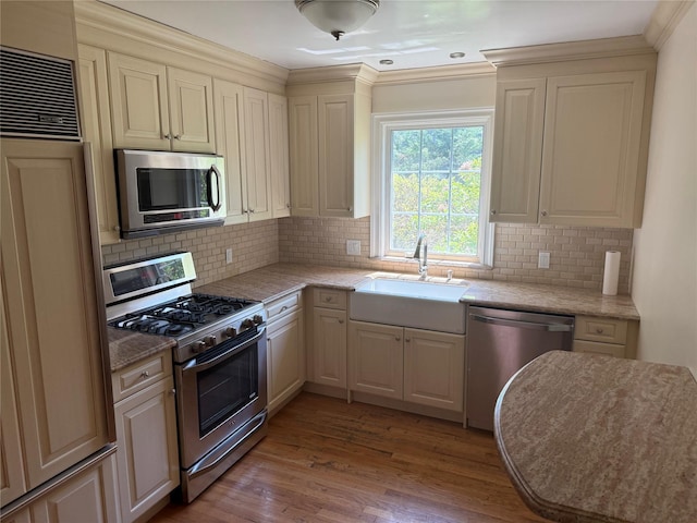 2330 Kingsland Ave, Bronx, NY 10469 - kitchen featuring appliances with stainless steel finishes, a sink, wood finished floors, backsplash, and crown molding