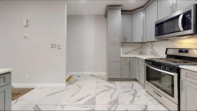 kitchen with light countertops, appliances with stainless steel finishes, gray cabinets, and baseboards