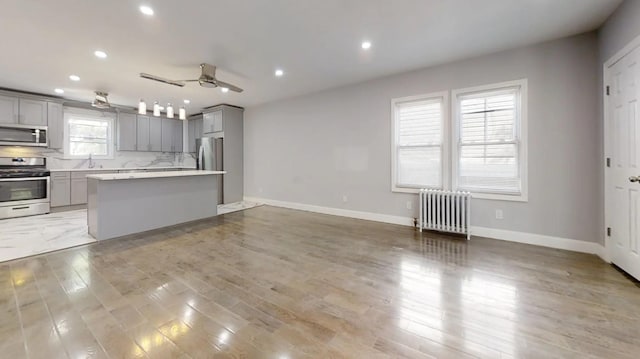kitchen featuring a ceiling fan, radiator, light countertops, appliances with stainless steel finishes, and gray cabinets