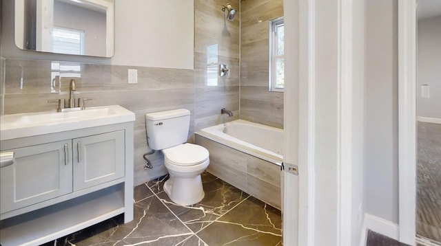 bathroom featuring tile walls, toilet, marble finish floor, tiled shower / bath, and vanity