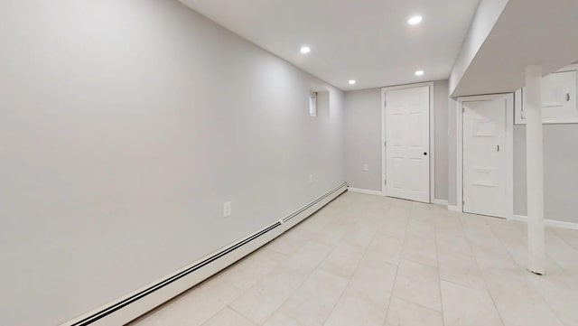 finished below grade area with a baseboard heating unit, baseboards, light tile patterned floors, and recessed lighting