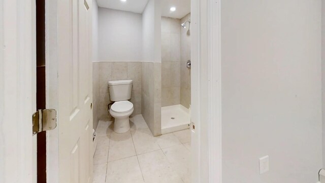 bathroom featuring tile walls, toilet, tile patterned flooring, and a stall shower