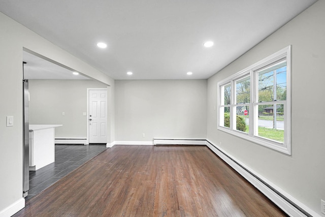 empty room with a baseboard heating unit, dark wood-type flooring, recessed lighting, and baseboards