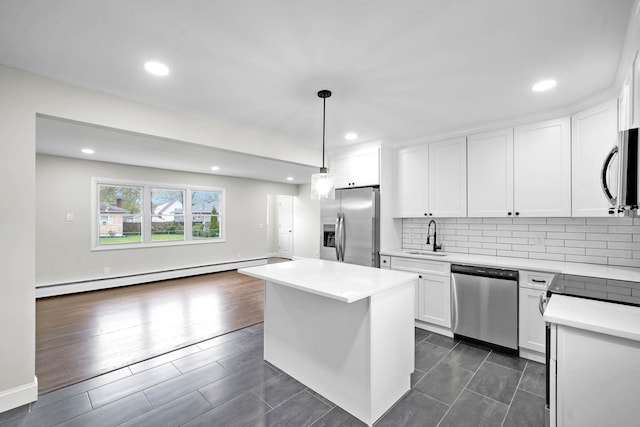 kitchen featuring stainless steel appliances, baseboard heating, a sink, tasteful backsplash, and white cabinets