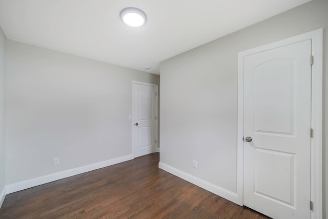 unfurnished bedroom featuring baseboards and dark wood-type flooring