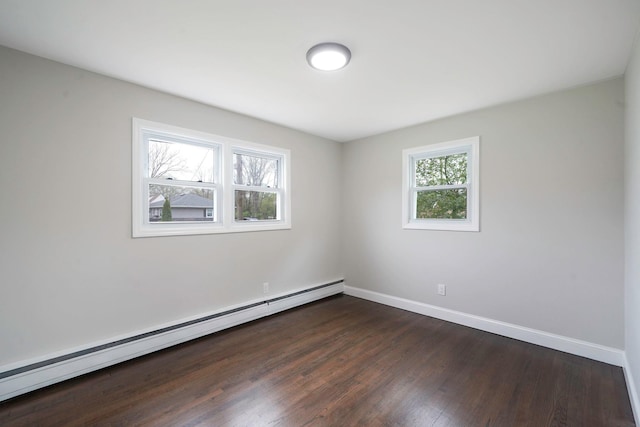 empty room featuring a baseboard heating unit, dark wood-type flooring, and baseboards