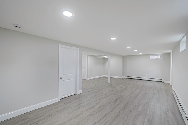 basement featuring baseboard heating, a baseboard radiator, light wood finished floors, baseboards, and recessed lighting
