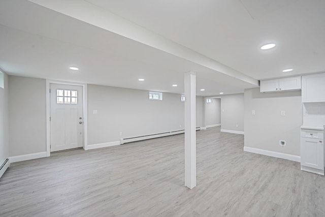 basement featuring a baseboard radiator, light wood-style floors, baseboards, and recessed lighting