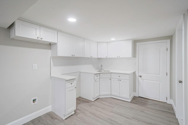 kitchen with a sink, light wood-style flooring, white cabinets, baseboards, and recessed lighting
