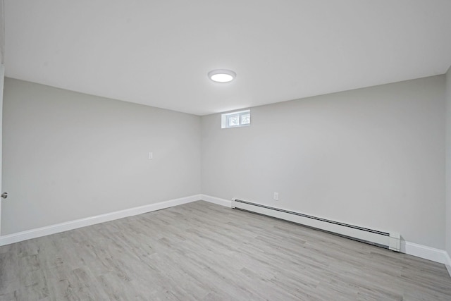 basement featuring a baseboard radiator, wood finished floors, and baseboards