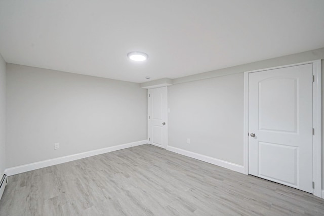 unfurnished room featuring wood finished floors, baseboards, and baseboard heating